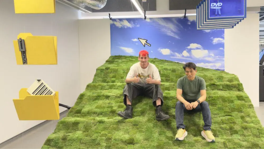 Owen and a staff member sat on the turf of the Microsoft Hill sculpture