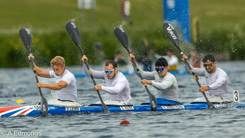 Four men canoeing on water.