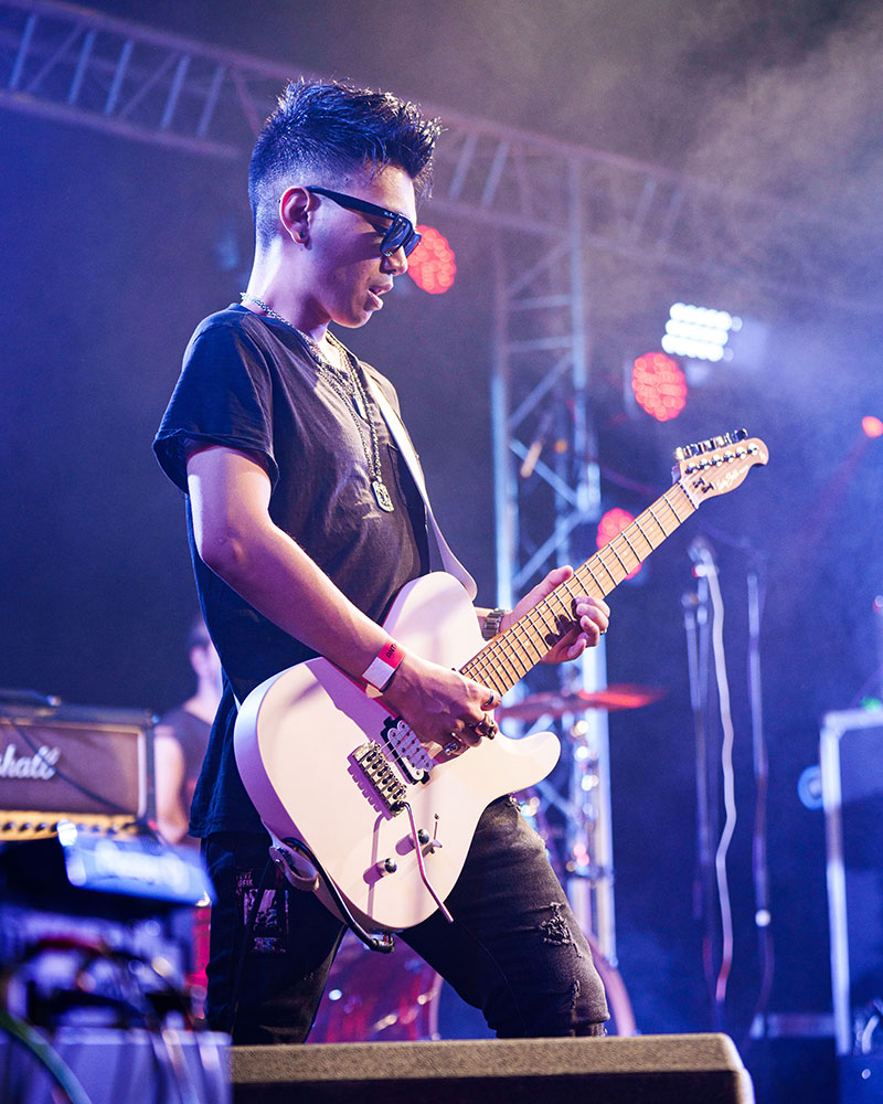 male performer in sunglasses playing the electric guitar
