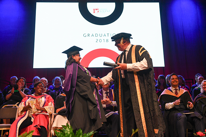 Nisha Haq receiving her honorary degree from the University's Chancellor, Lord West