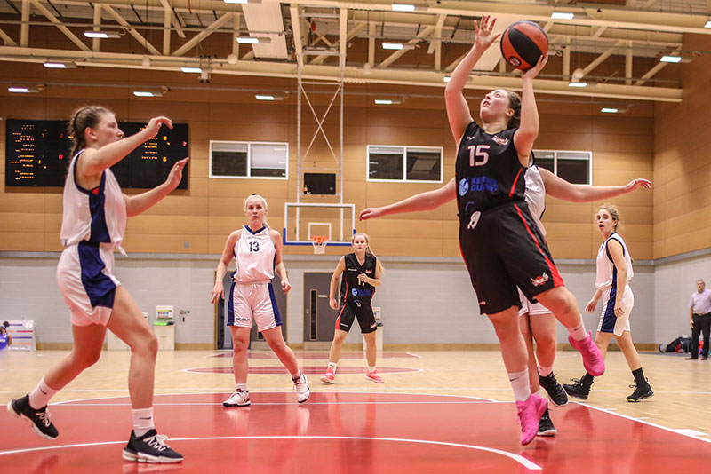 A Team Solent basketball player taking a shot during a match