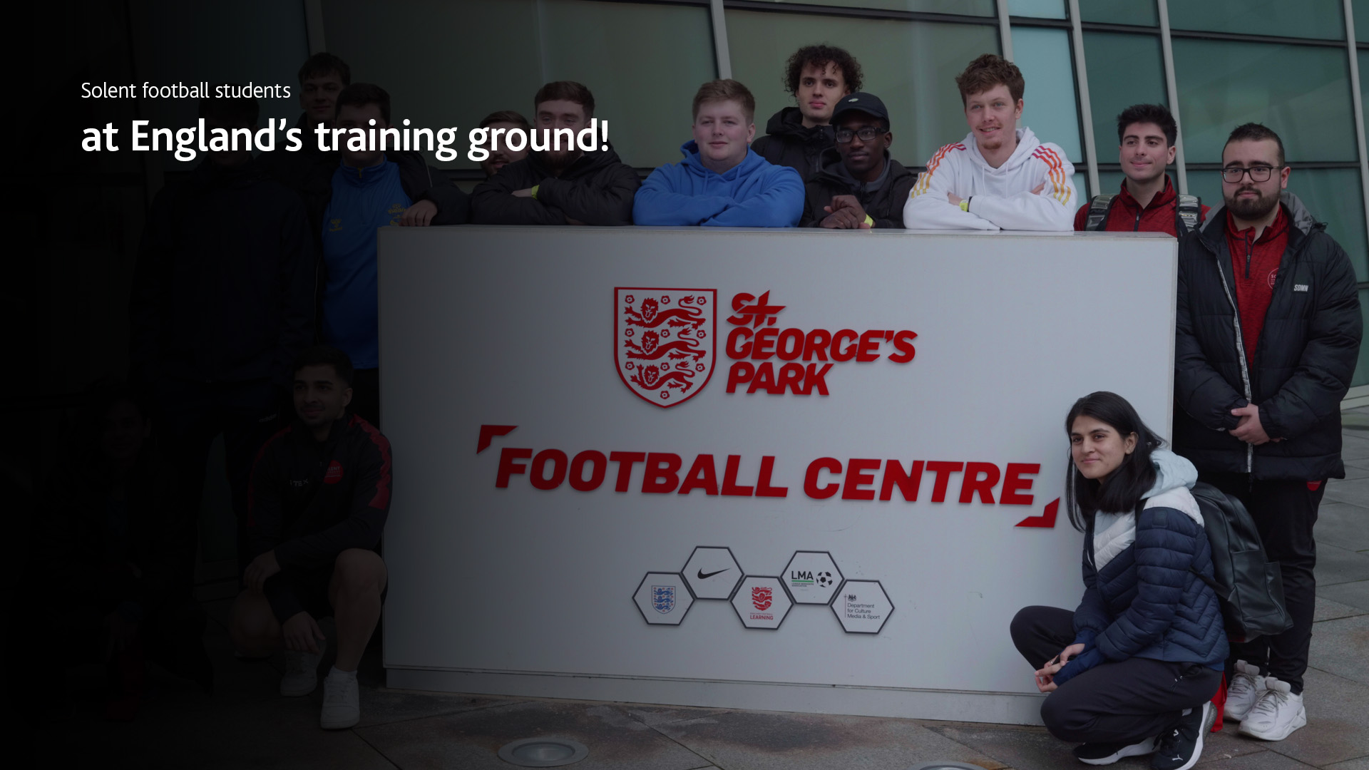 Solent students at St George's Park, posing with a sign saying 'St George's Park Football Centre'.