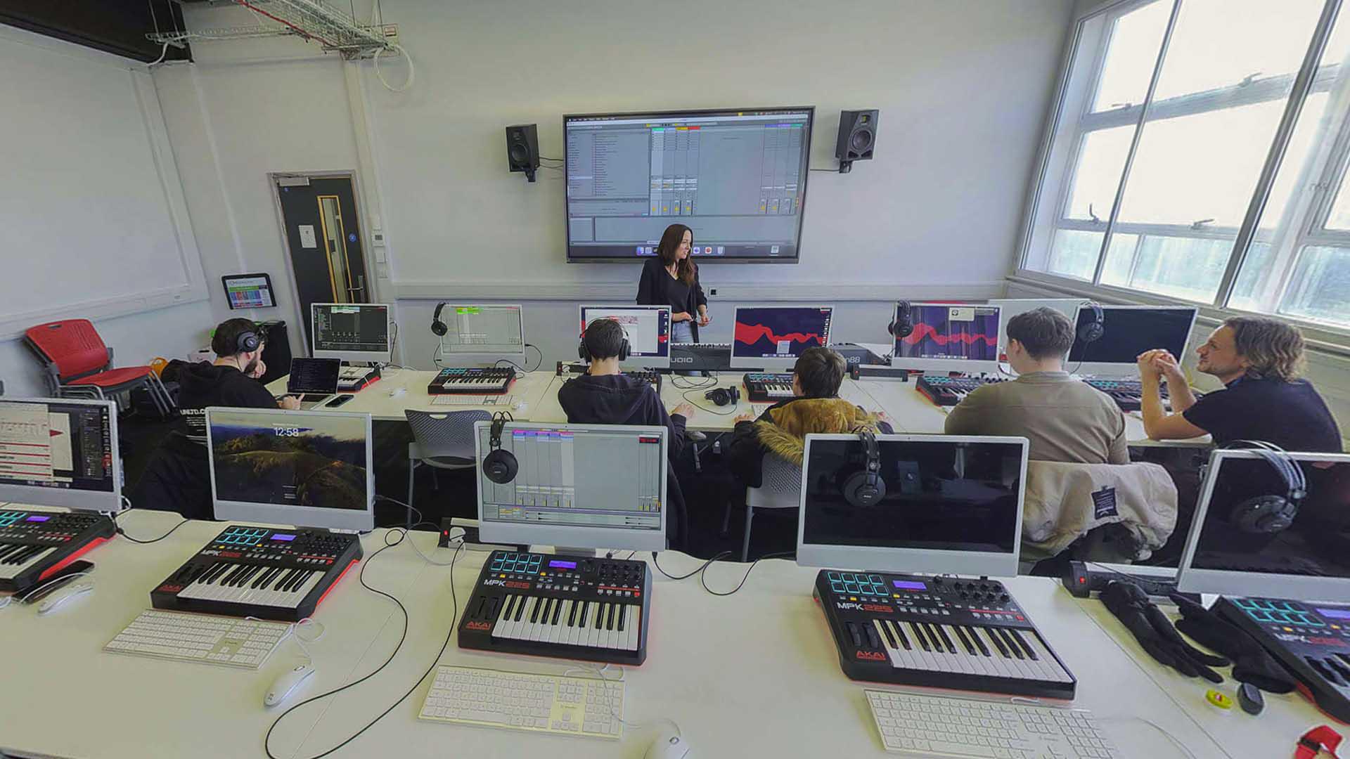 Digital music students and teacher in classroom with consoles
