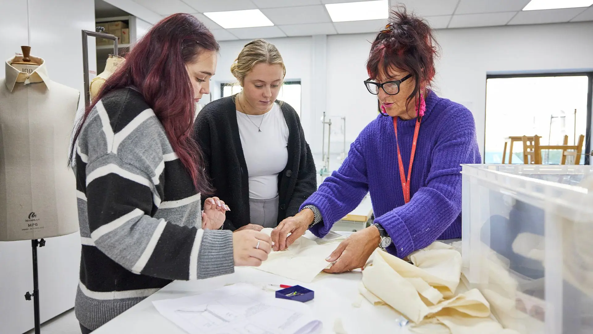 Students being shown techniques by lecturer in fashion design studio