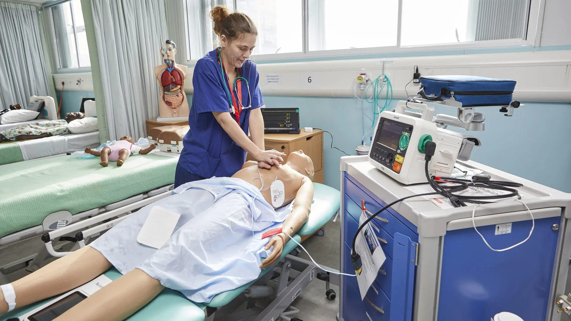A nursing lecturer performing CPR on a dummy patient