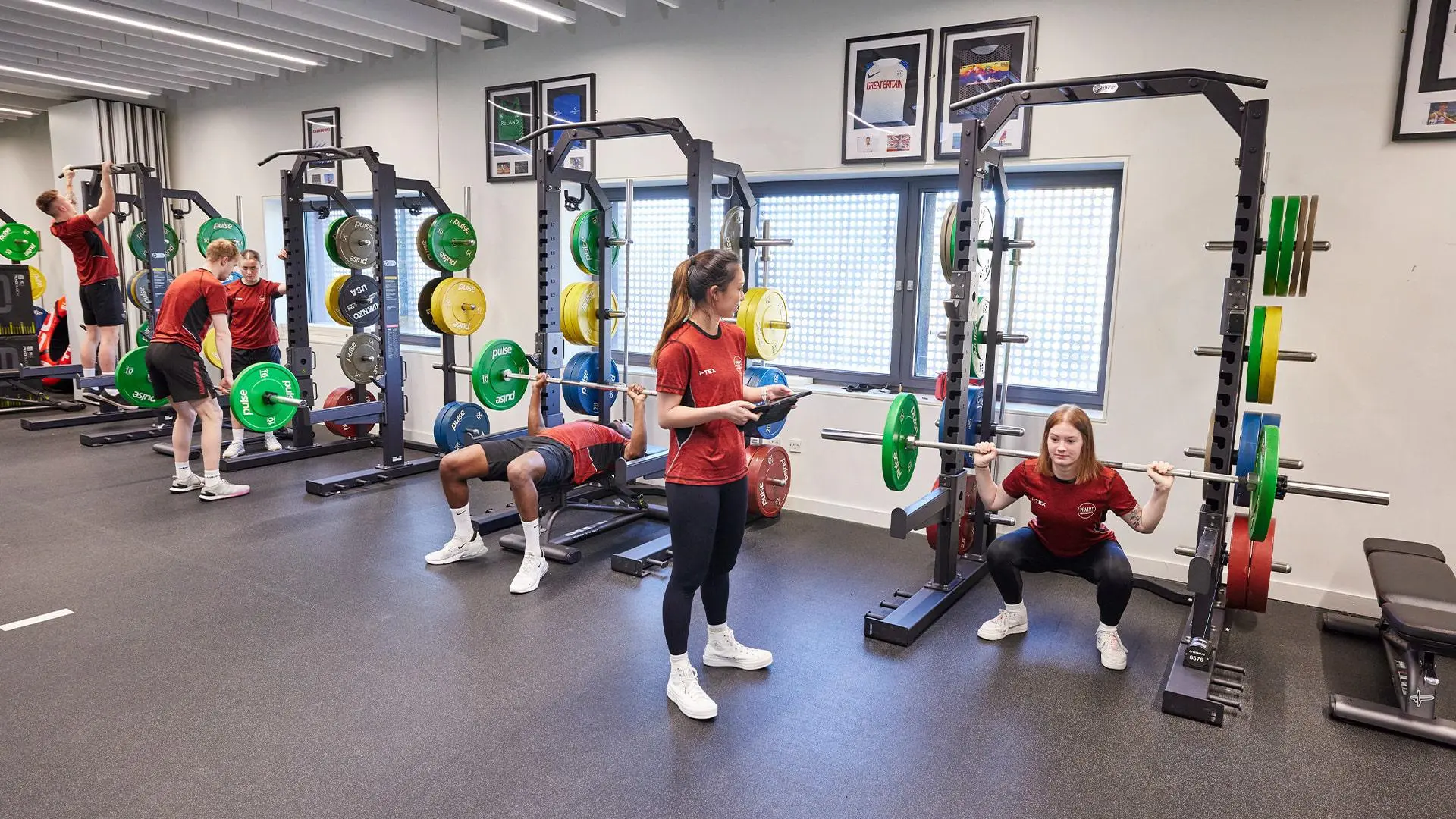 Students using squat racks in teaching gym