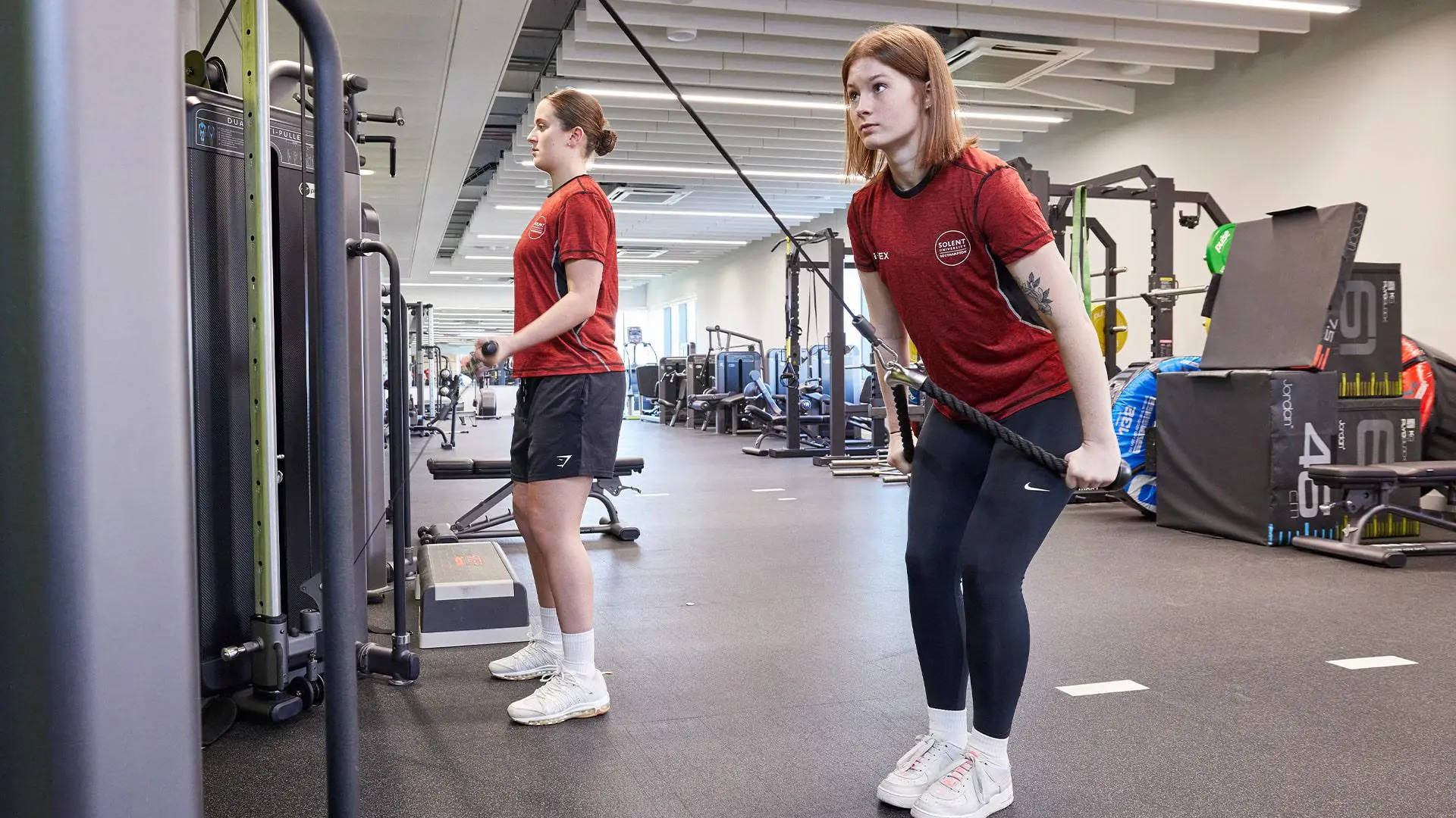 Students using cable weights machines in teaching gym