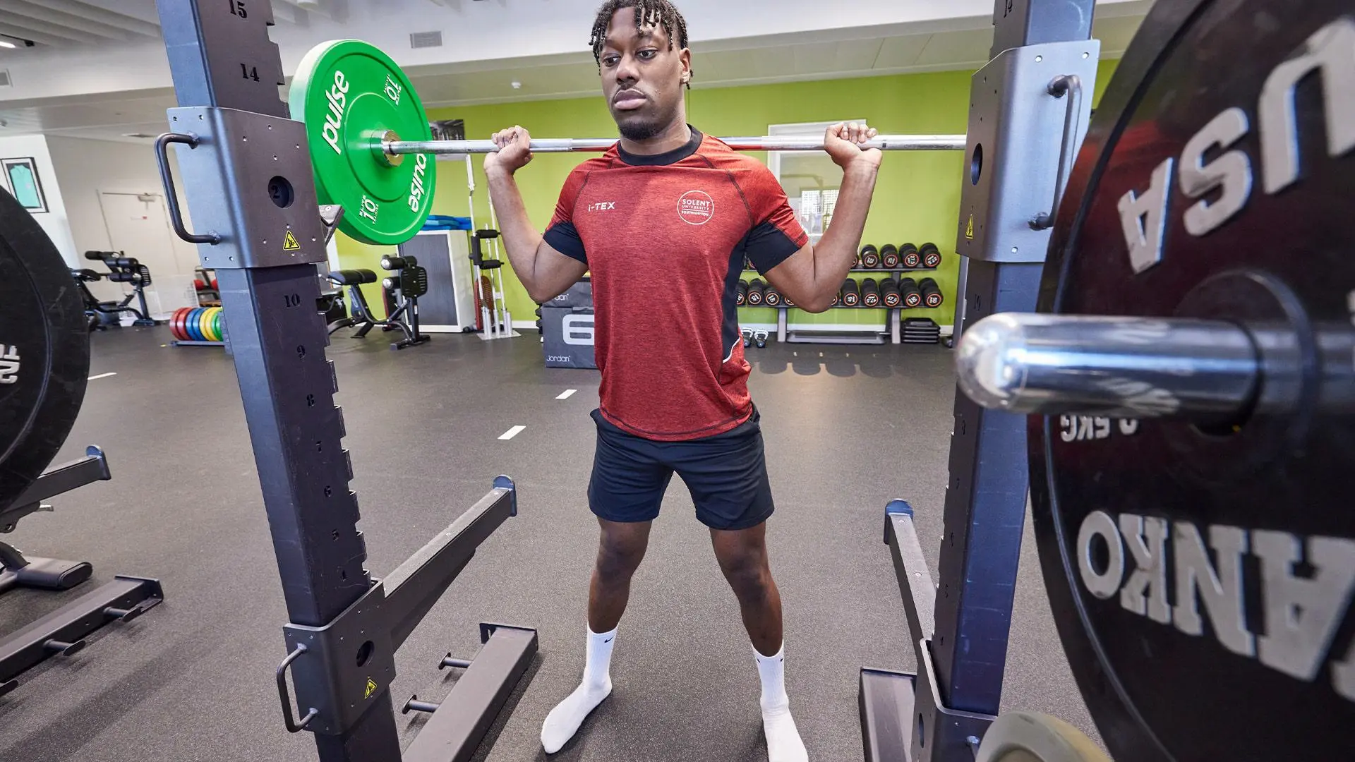 Student using squat rack in teaching gym