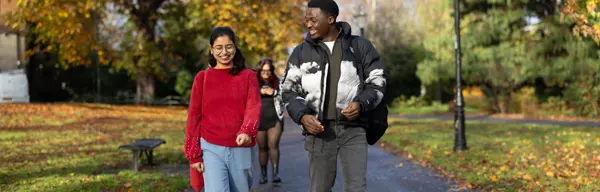 Two students walking through an autumnal park