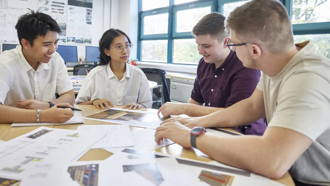 Four architecture students studying drawings