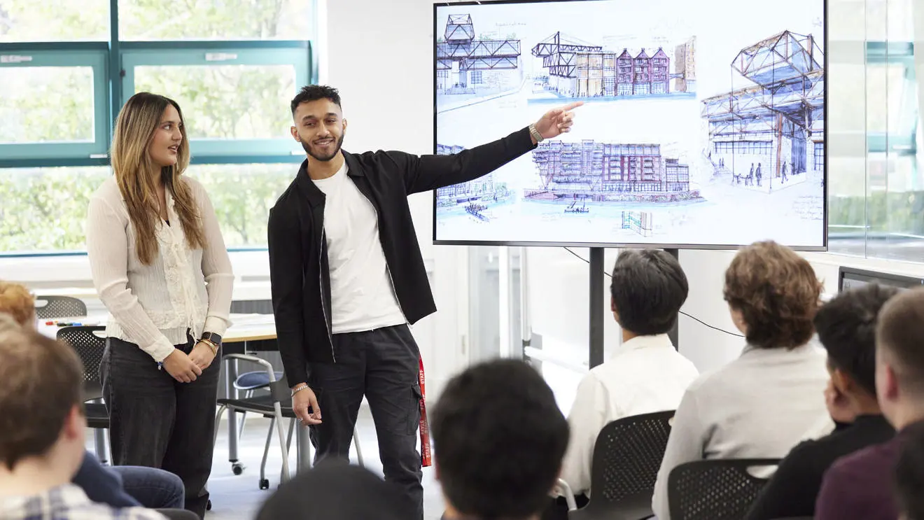An architecture student pointing to drawings on a screen in a presentation