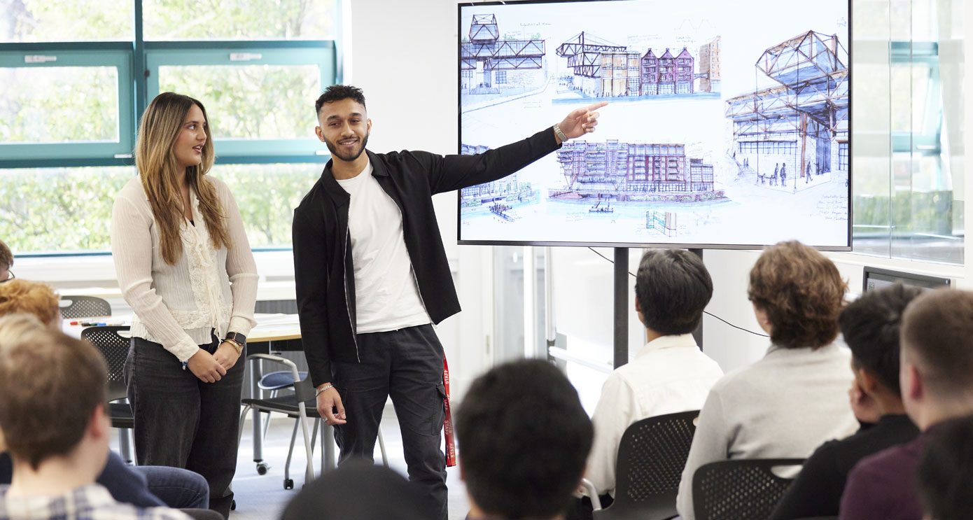 An architecture student pointing to drawings on a screen in a presentation