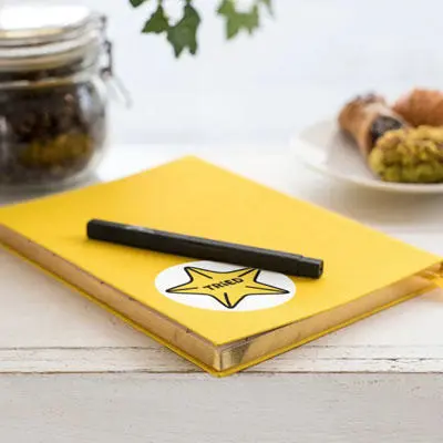 A yellow notebook with a star sticker and a pen laying on top