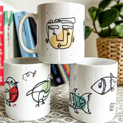 Three mugs stacked on top of each other with continuous line art designs on them