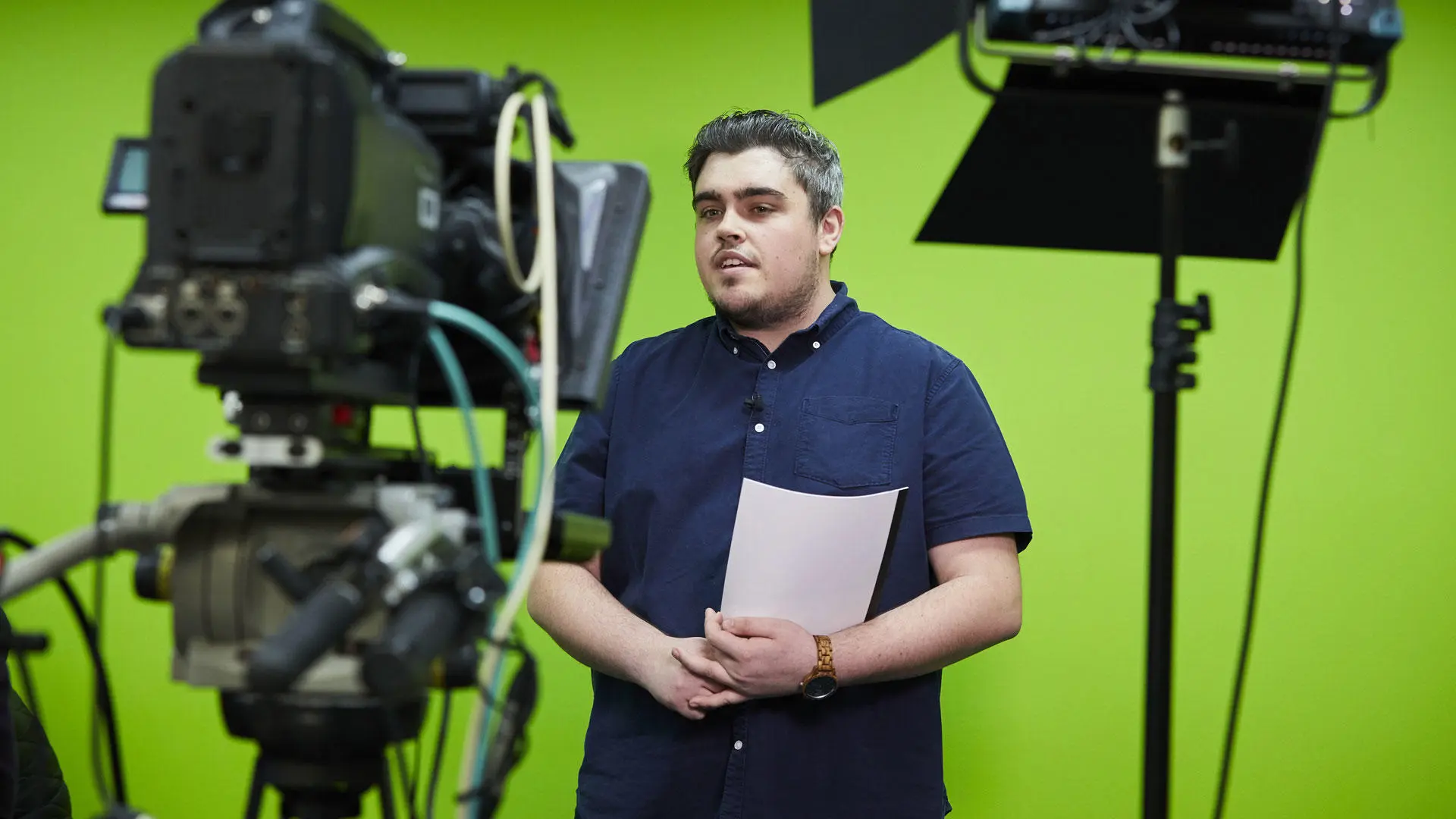 A sport journalism student standing in front of a green screen
