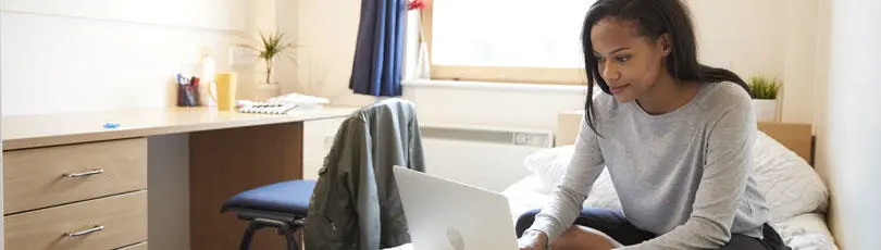 A student in her room looking at a laptop