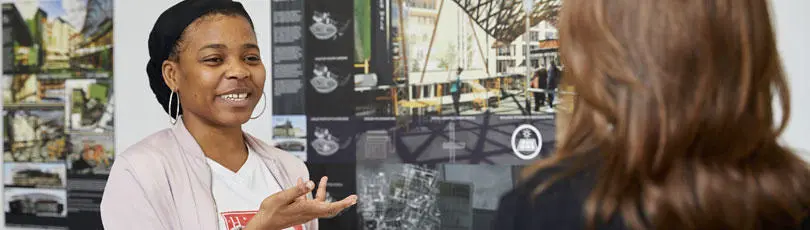 A student standing in front of her work talking to someone
