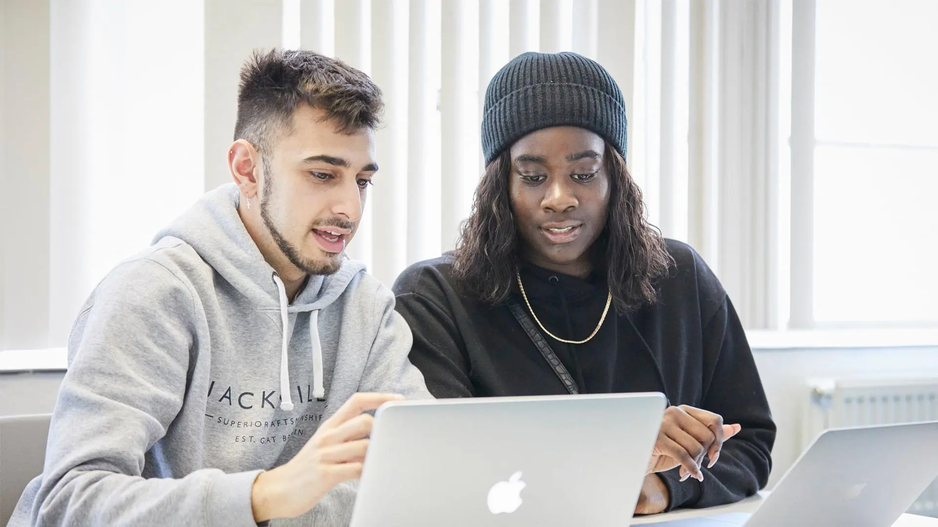Image shows two students working on a laptop