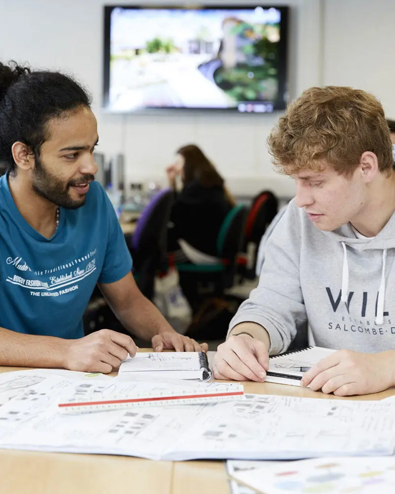 Two architecture students looking at drawings in the studio