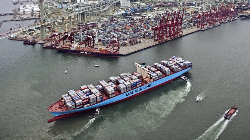 A Maersk container ship leaving a busy port