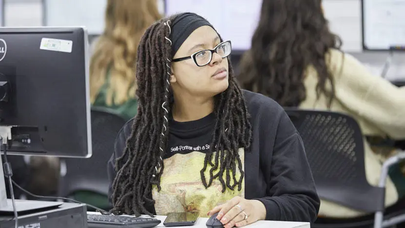 A female student sat at a desktop computer