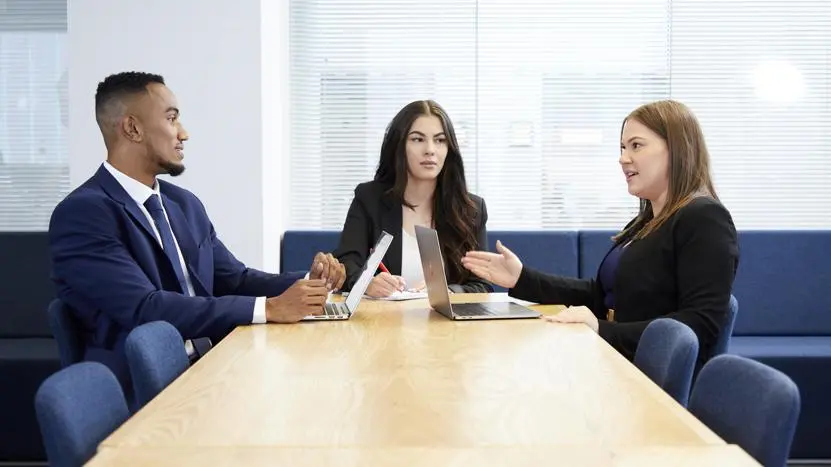 Image of three people working at a desk in a corporate environment