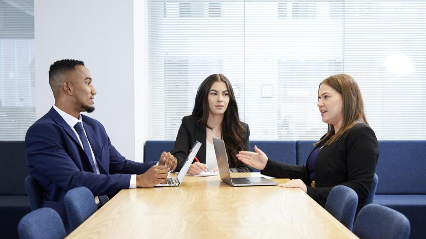 Image of three people working at a desk in a corporate environment