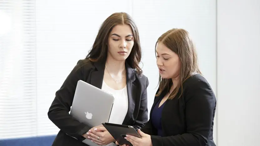 Image of two office workers looking at a laptop