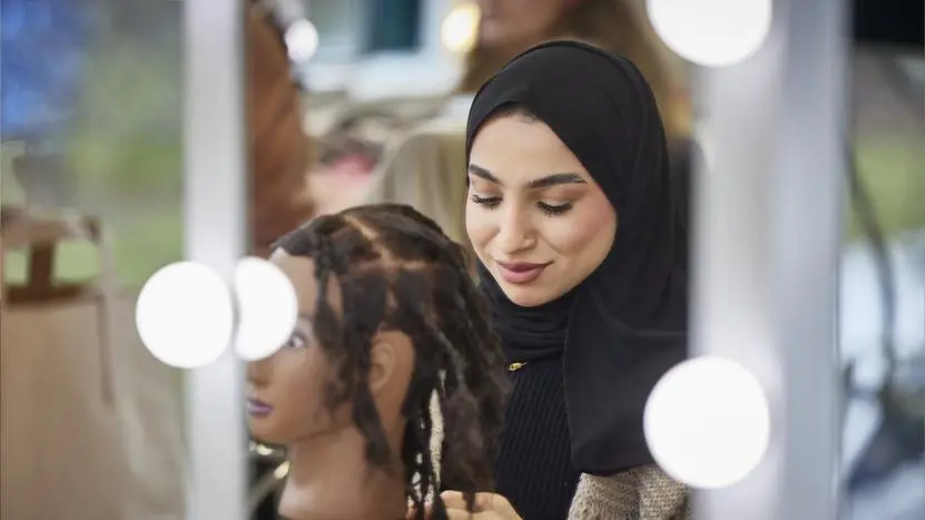Image of person working on a mannequin's hair design