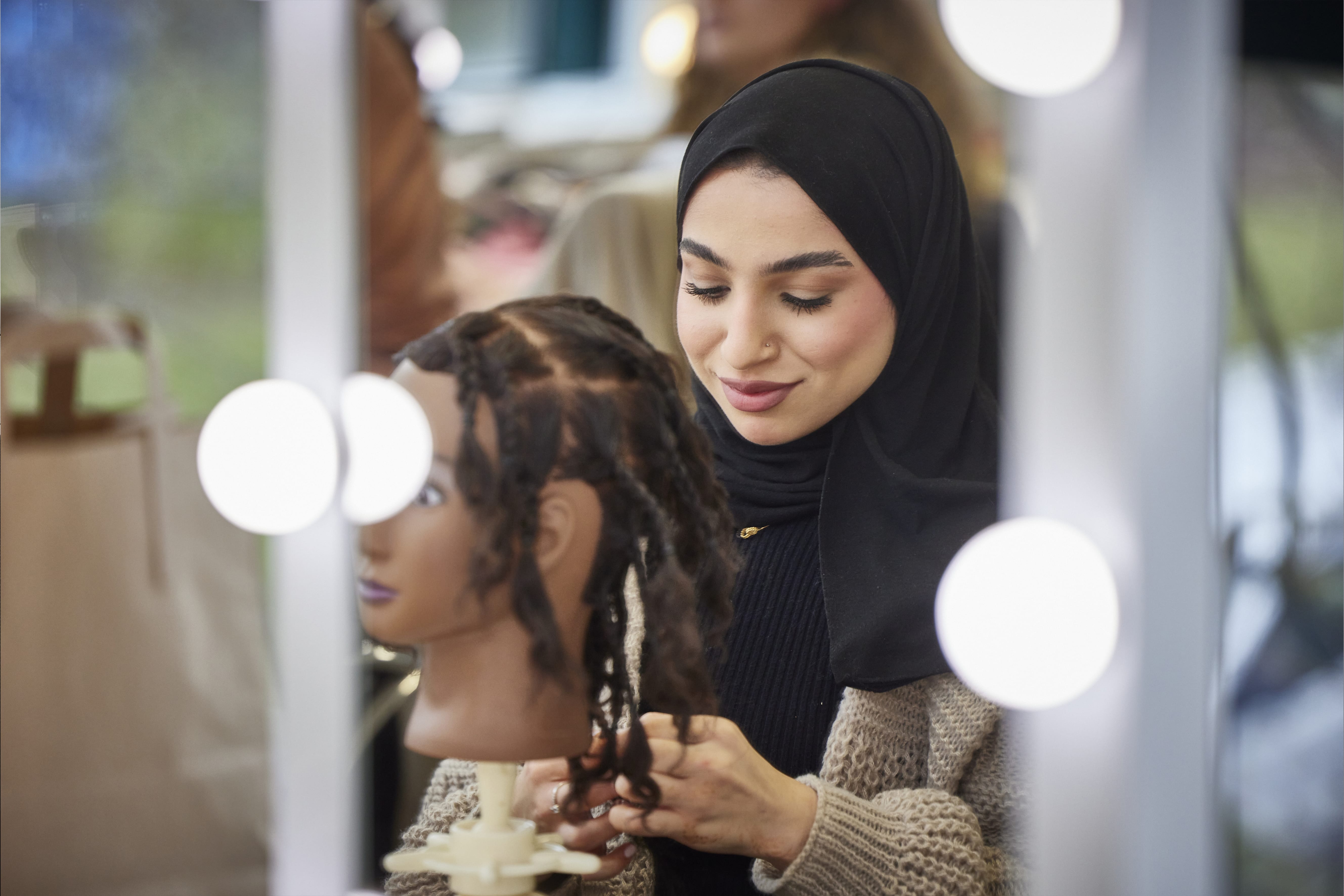Image of person working on a mannequin's hair design