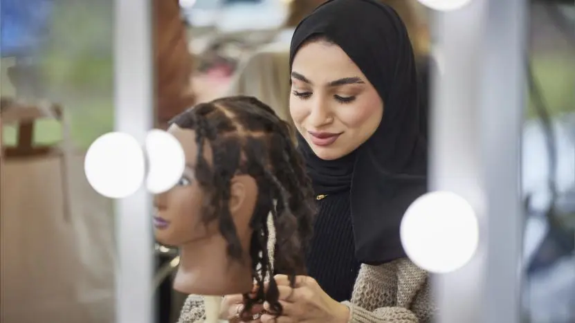 Image of person working on a mannequin's hair design