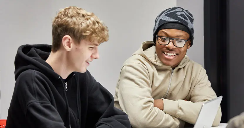 Two male students talking to each other in a classroom