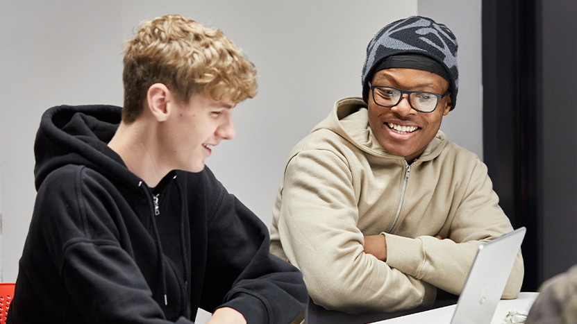 Two male students talking to each other in a classroom