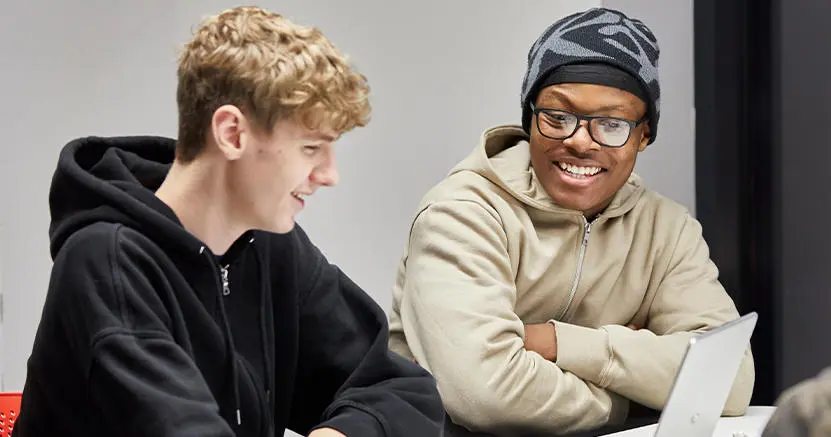 Two male students talking to each other in a classroom