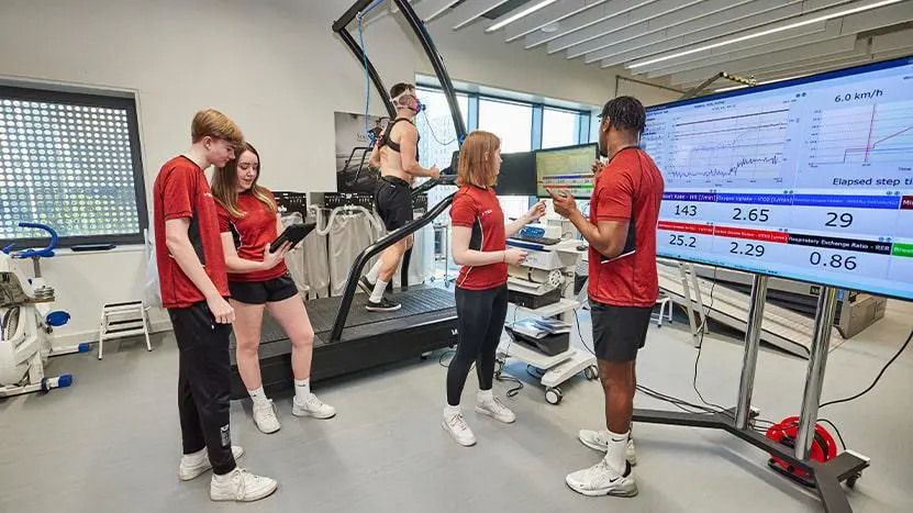A group of sport science students working with a client in the physiology lab