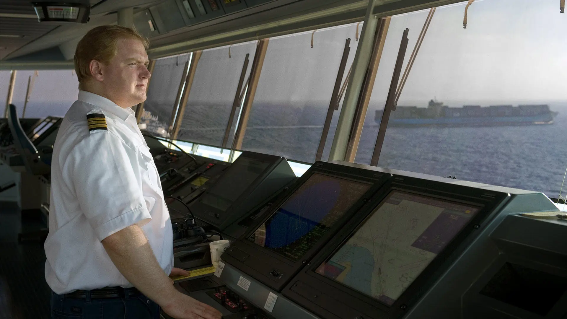 A ship's captain on the bridge looking out the windows