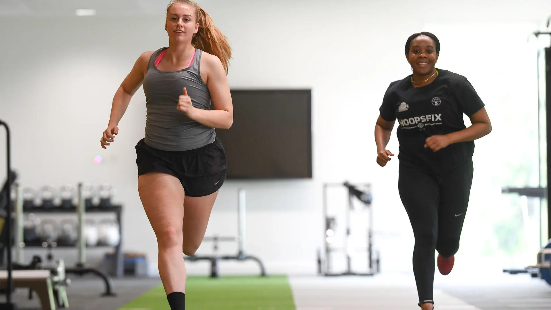 Two athletes running in the gym