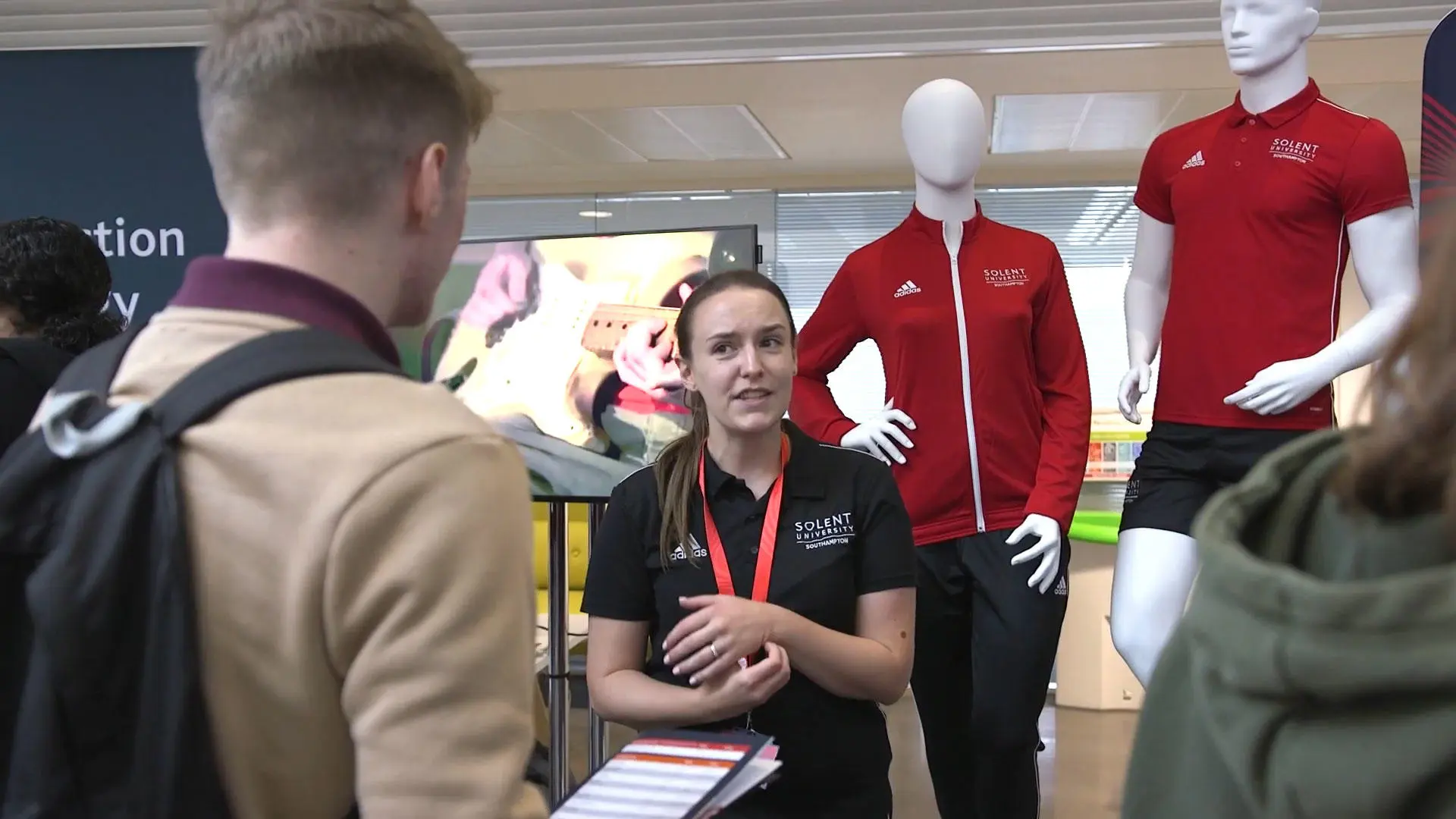 People talking to a sports lecturer at an open day