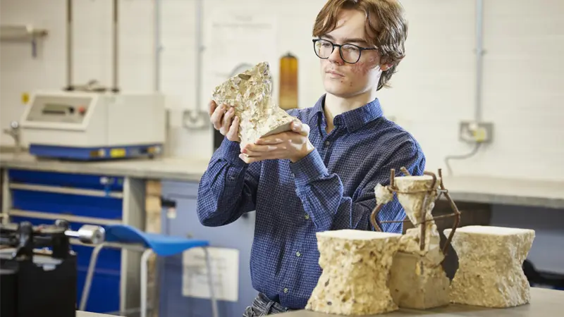 A student inspecting concrete blocks in the construction lab