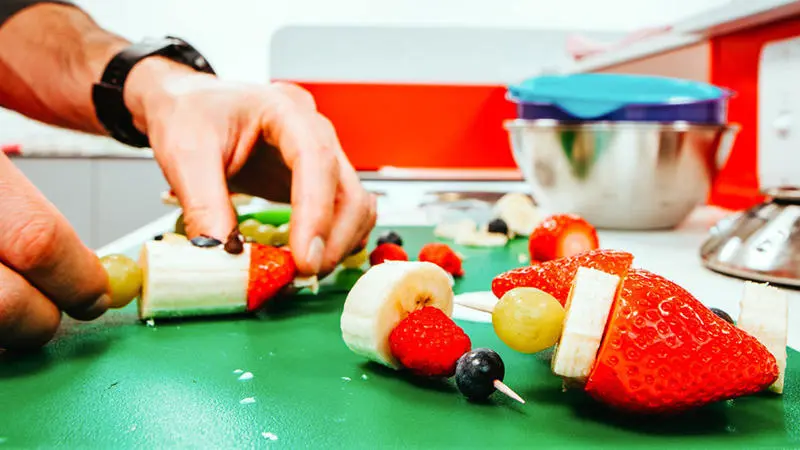 A person preparing fruit kebabs