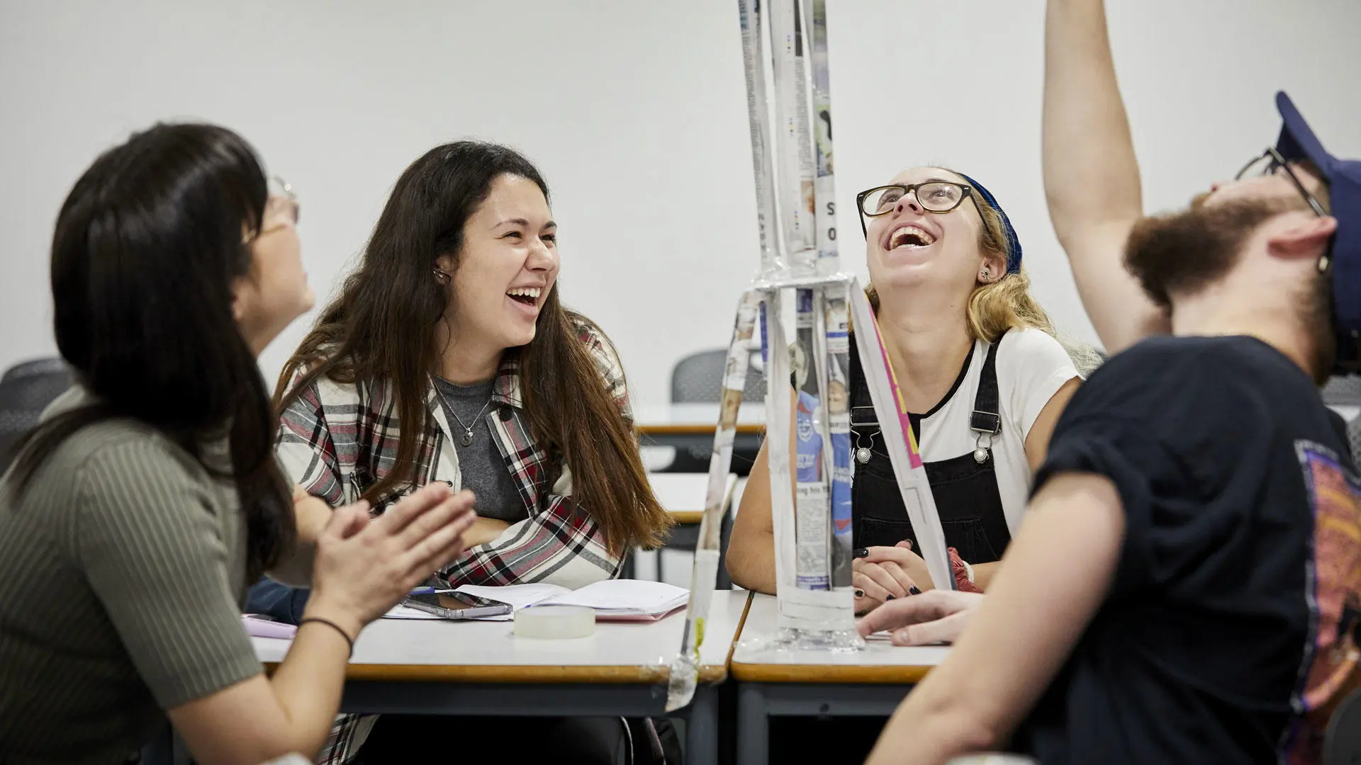 Four project management students working on a project and laughing with each other