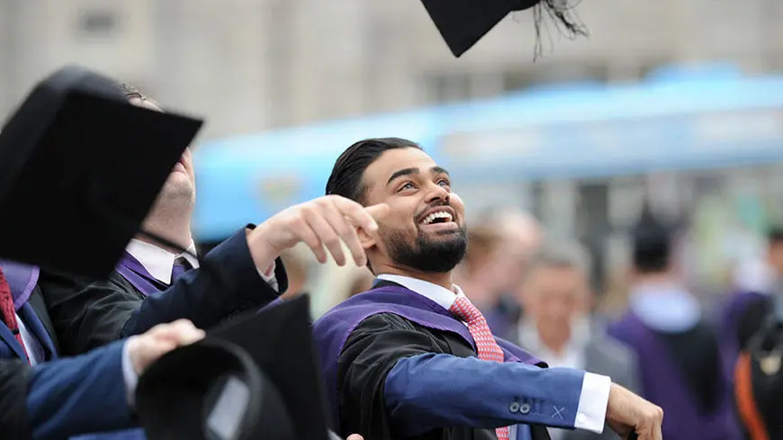 A male graduate throwing his cap in the air