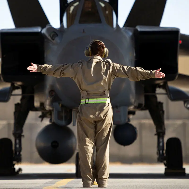 An armed forces person directing an army plane