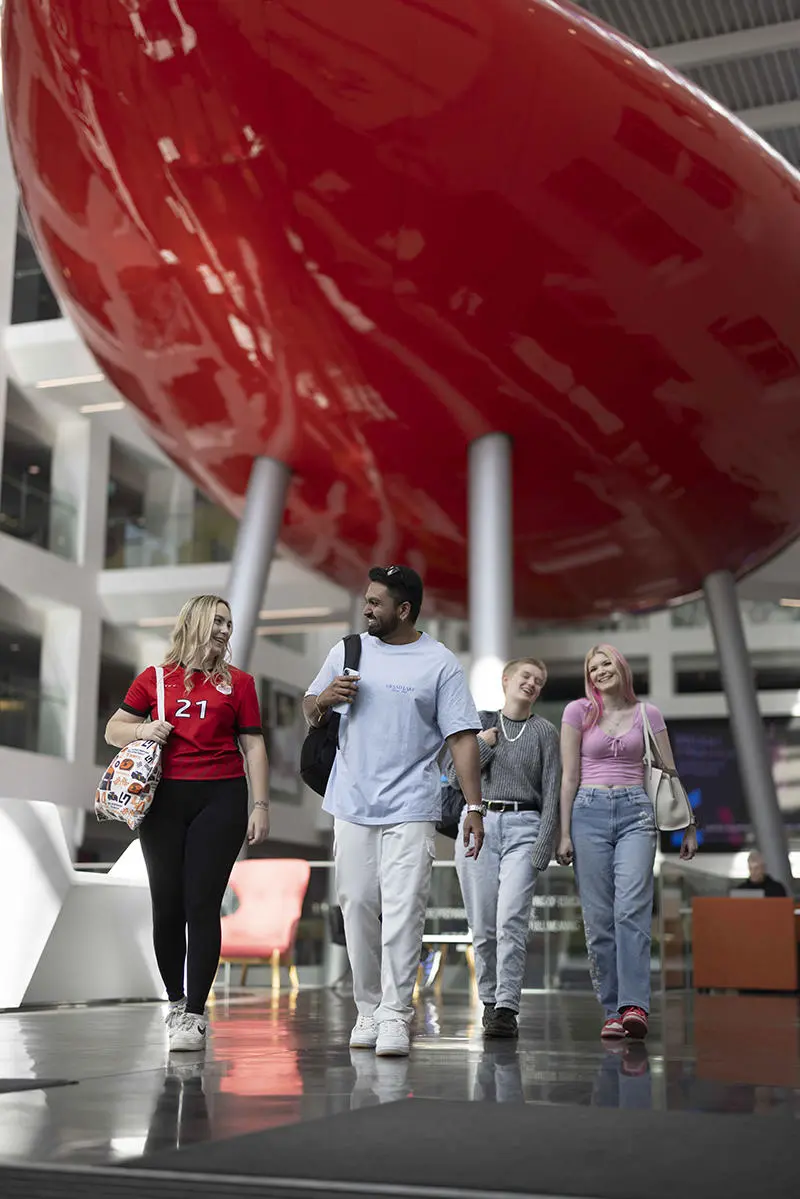 Four students walking in the Spark with the Pod in the background