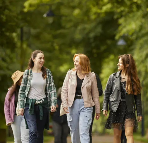 Three female students walking through the park