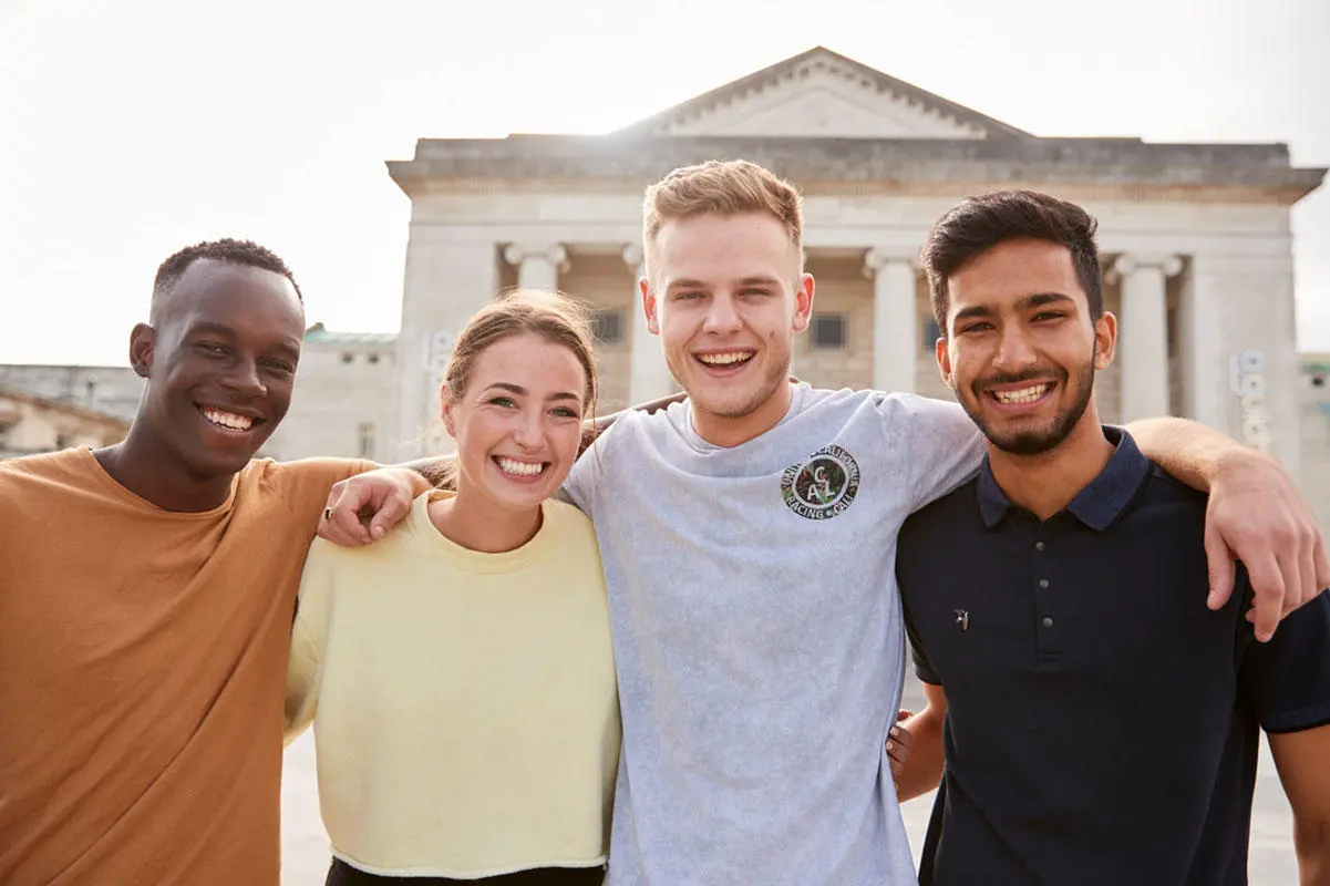 Four students with their arms around each other's shoulders