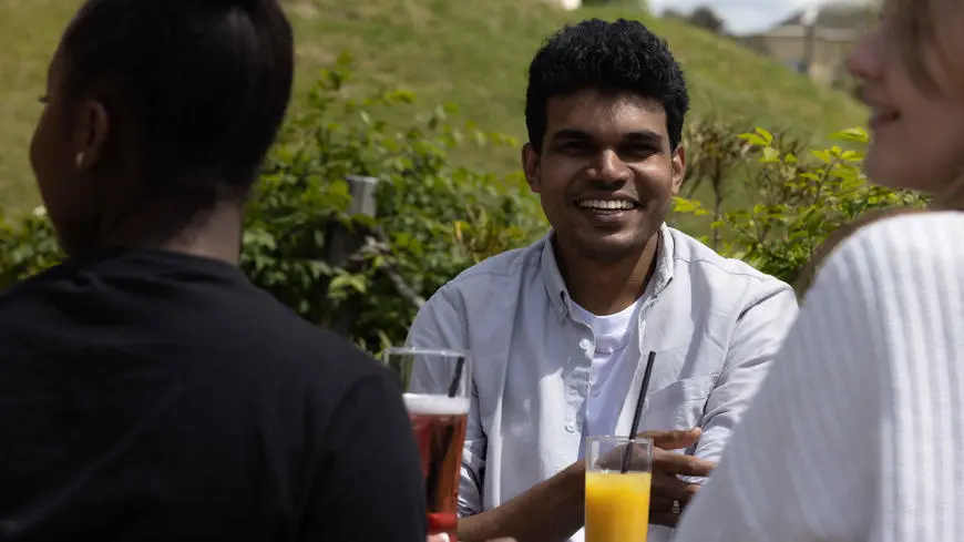 Solent student sat drinking an orange juice in Southampton City