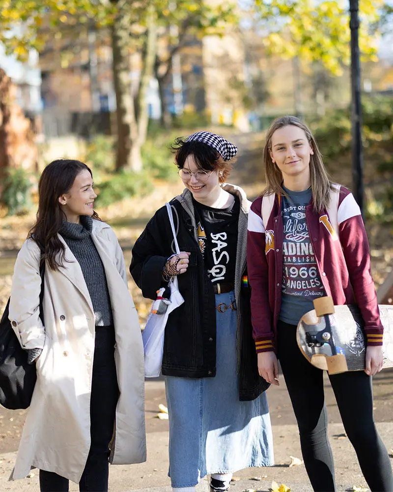 Three female students walking through the park