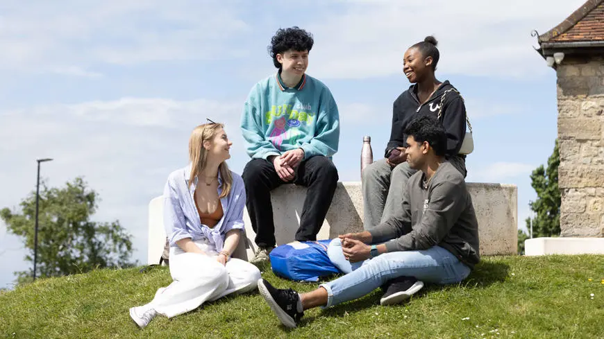 Four students sat on grass