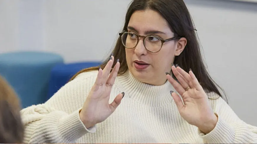 A female student wearing glasses gesturing with her hands